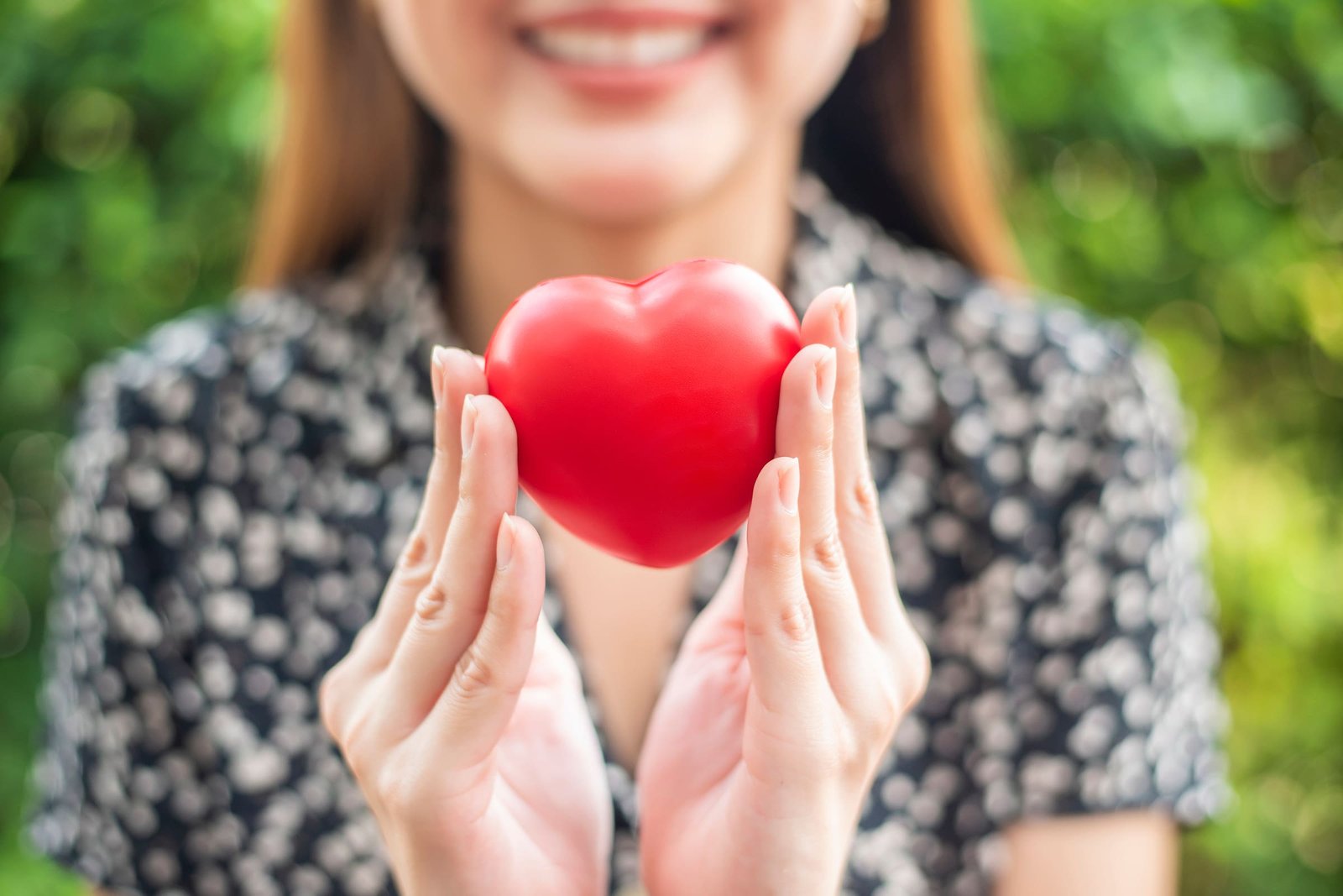 Smiling woman holding a red heart — Women's Health Acupuncture at Indigo Wellness Clinic, Coquitlam