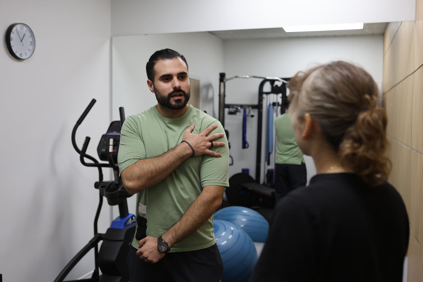 Kinesiologist consulting with a client on shoulder rehabilitation at Indigo Wellness Clinic, Coquitlam